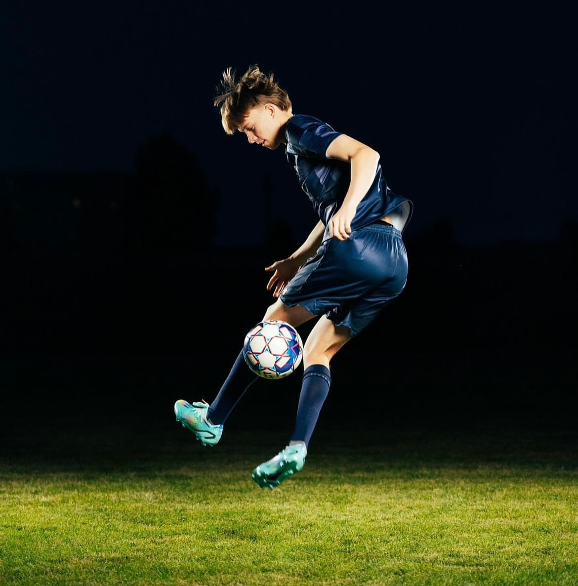 a football player bouncing a ball at night